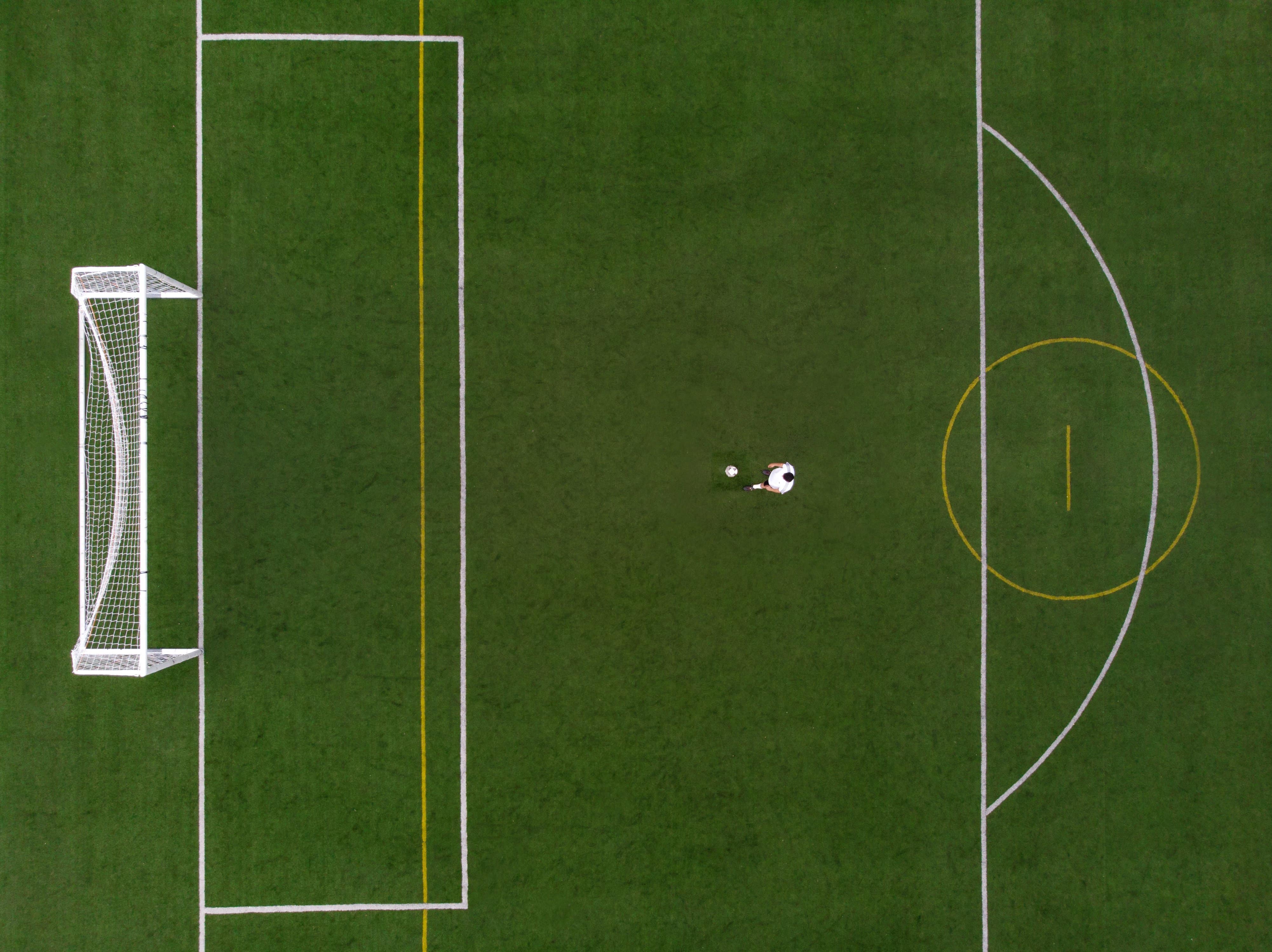 Overhead view of soccer field with player standing in front of the penalty box.