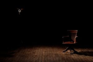 An empty chair in a dark room representing a person who has passed
