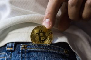 A person placing a bitcoin in their pocket